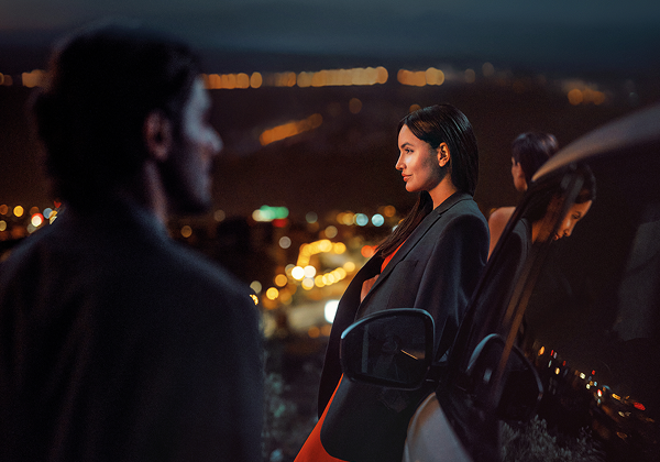 Naine seisab pimedas auto kõrval.