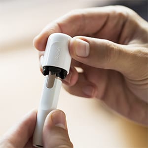 Käed hoiavad ja puhastavad IQOS 2.4 PLUS hoidjat